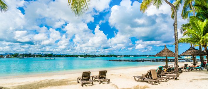 Sonnenliegen und Palmen am Strand von Grand Baie auf Mauritius