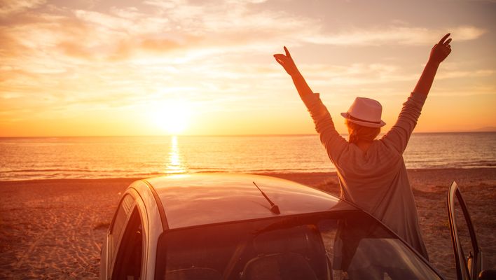 Frau bei Sonnenuntergang im Auto