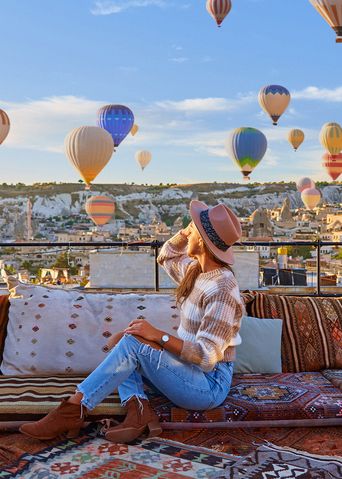 Reisende sitzen auf einer Terrasse und frühstücken mit Blick auf Ballons