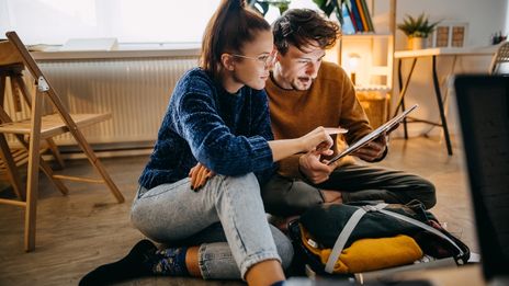 Pärchen mit Tablet beim Kofferpacken