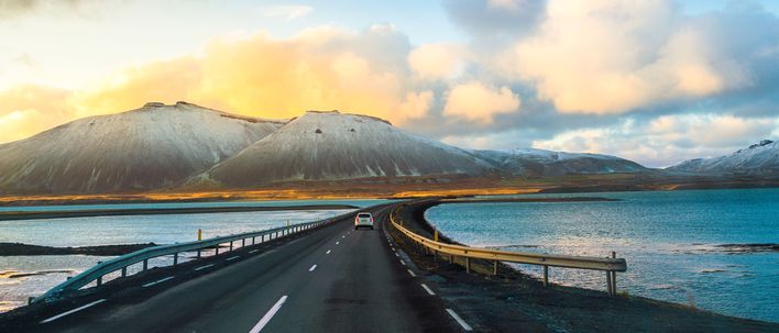 Auto fährt auf einer Straße durch die Landschaft Islands