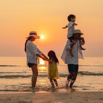 Familie in den Sommerferien bei Sonnenuntergang am Strand