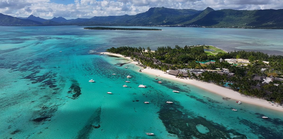 Luftaufnahme vom Strand von Le Morne auf Mauritius mit türkisblauem Meer und Booten vor der Küste