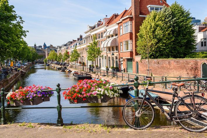 Idyllischer Kanal in Den Haag mit Blumen, historischen Häusern und Fahrrad auf der Brücke