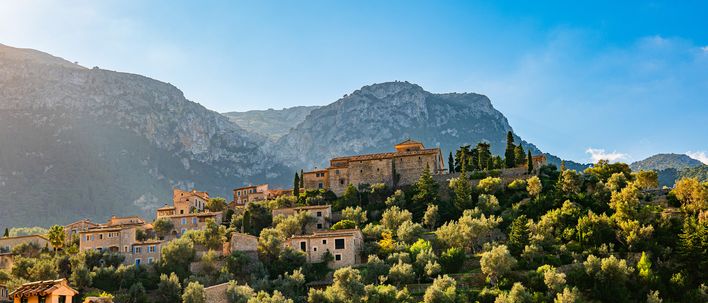 Blick auf das Bergdorf Deia auf Mallorca, umgeben von Olivenhainen und der Serra de Tramuntana