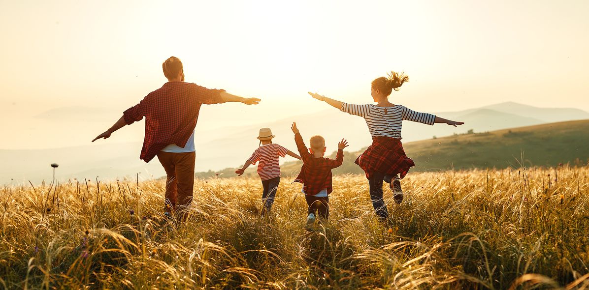 Familie läuft fröhlich durchs Feld