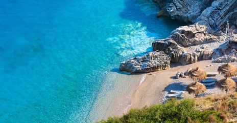  Der malerische Strand von Himare an der albanischen Riviera mit türkisfarbenem Wasser und Sonnenschirmen