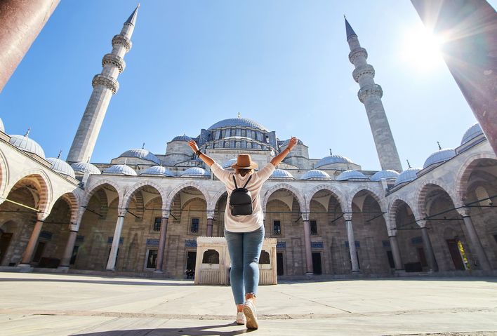 Frau steht im Innenhof einer Moschee in Istanbul mit Blick auf Kuppeln