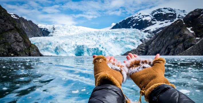 Hände zeigen auf eine Eiswand eines Gletschers mit blauem Eis in Alaska