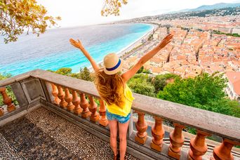 Eine Frau steht auf einer Terrasse mit Blick auf die Stadt Cannes