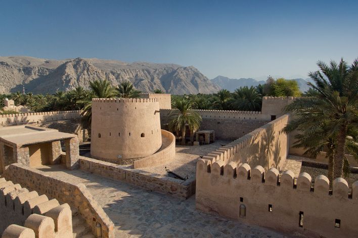 Historische Gebäude und Festung von Khasab in Oman vor Bergkulisse und Palmen