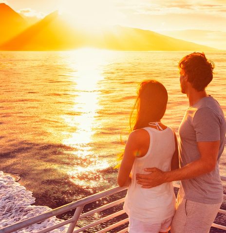 Paar steht an Deck und beobachtet den Sonnenuntergang