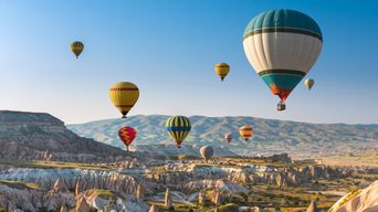 Heißluftballons steigen über Felsformationen in Kappadokien bei Sonnenaufgang