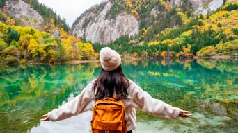 Frau schaut auf eine Herbstlandschaft im Jiuzhaigou-Nationalpark in Sichuan, China