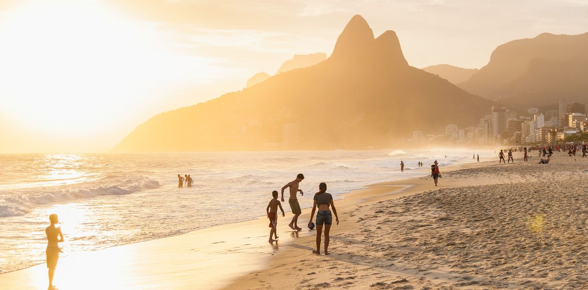 Menschen am Ipanema Beach in Rio de Janeiro bei Sonnenuntergang