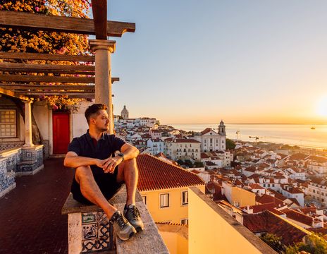 Mann genießt bei einem Sonnenuntergang den Blick auf die Stadt Lissabon
