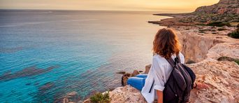 eine Frau schaut auf das Meer bei Sonnenuntergang