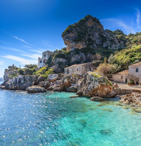 Kleine Bucht mit Häusern und glitzerndem Meer in Scopello auf der italienischen Insel Sizilien