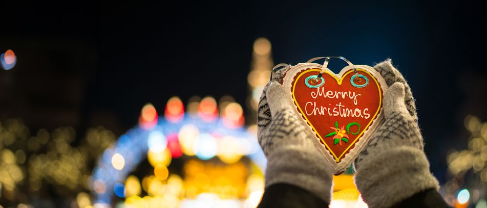 Hände halten Lebkuchenherz im Hintergrund Weihnachtsmarkt 