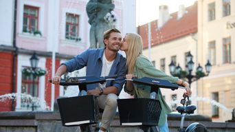 Junges Paar auf Fahrrädern vor historischem Stadtplatz in Tartu, Estland