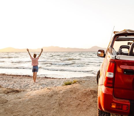 Frau am Strand mit Auto