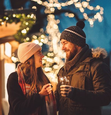 Paar mit Wunderkerzen am Weihnachtsmarkt