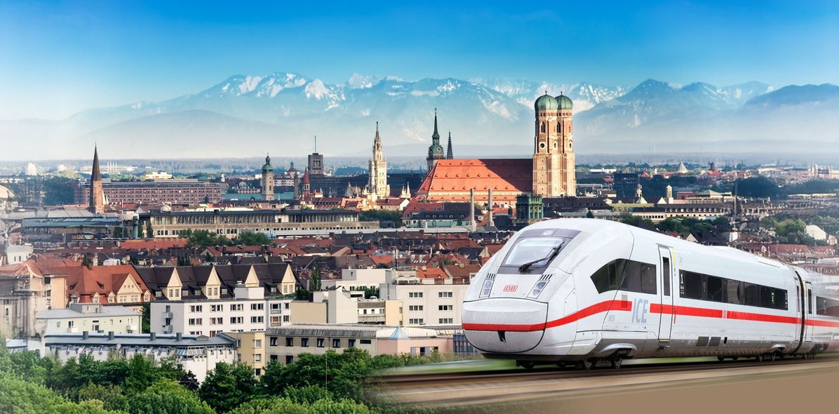 Panoramabild von München mit Frauenkirche und Bergen mit einen ICE im Vordergrund