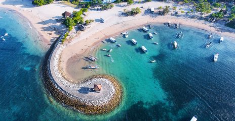 Luftaufnahme der geschwungenen Bucht von Nusa Dua mit Booten