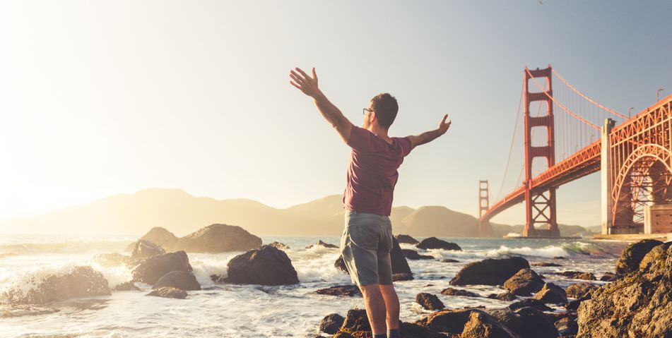 Ein Mann steht unterhalb der Golden Gate Bridge in San Francisco