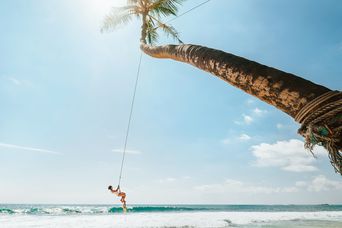 Reisende schaukelt an einer Palme über dem Meer an einem tropischen Strand in Sri Lanka