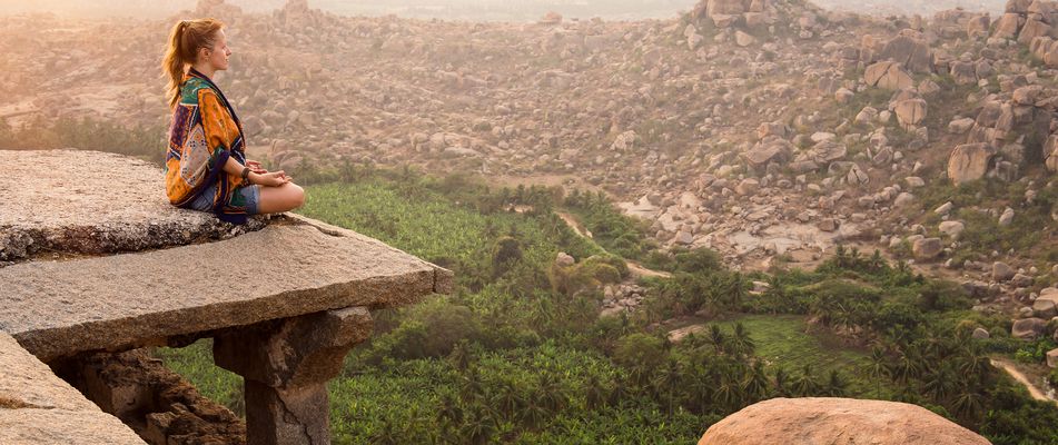 Frau meditiert auf Felsen von Hampi