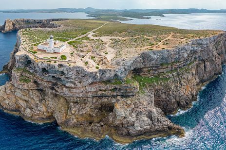 Luftaufnahme vom Leuchtturm am Cap de Cavalleria auf Menorca auf einer Felsklippe über dem Meer