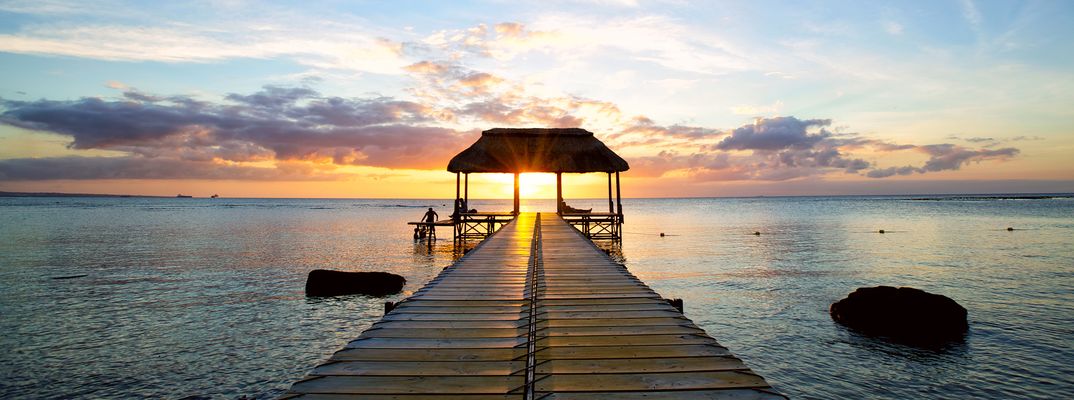 Romantischer Holzsteg am Strand von Mauritius bei Sonnenuntergang