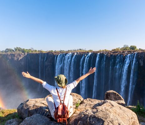 Frau sitzt auf Felsen bei den Viktoria Fällen