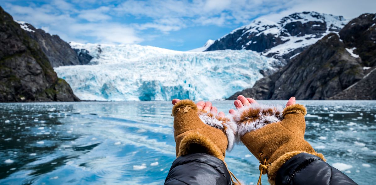 Hände zeigen auf eine Eiswand eines Gletschers mit blauem Eis in Alaska