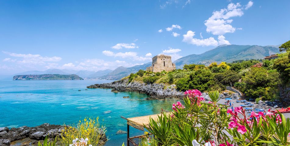 Küstenlandschaft in Kalabrien mit Felsen, blauem Meer und bunten Blumen