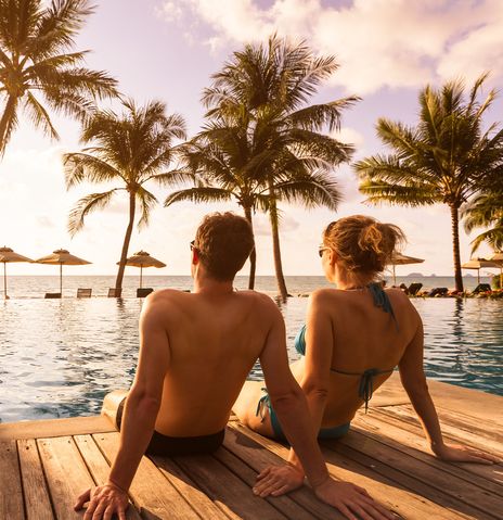 Paar sitzt am Pool und genießt die Sonne