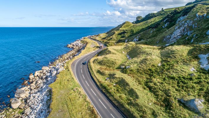 Mietwagen fährt auf einer Straße an der Küste von Irland