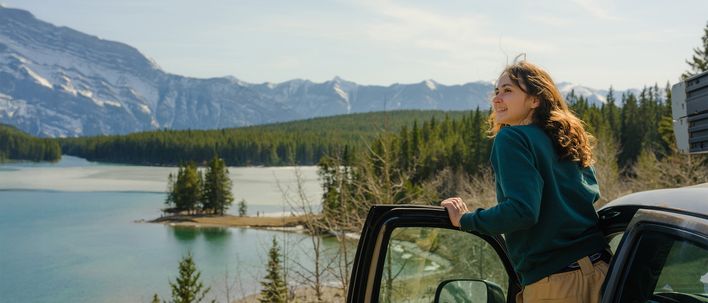 Frau steigt aus ihrem Auto aus und blickt auf die Landschaft im Banff Nationalpark, Kanada