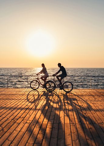 Fahrradfahrer am Meer im Sonnenuntergang