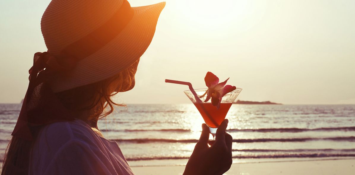 Frau mit Cocktail am Strand