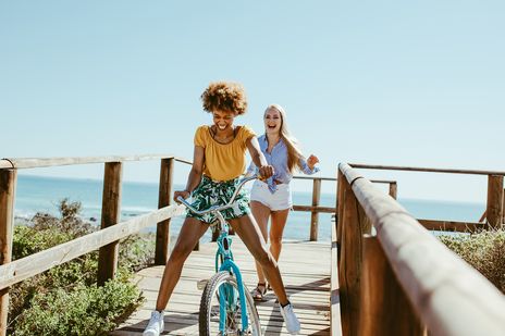 Frauen am Meer auf Fahrrädern und haben Spaß