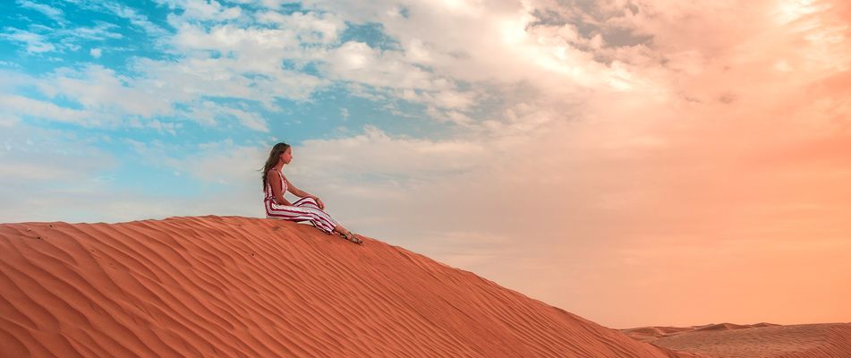 Eine Frau sitzt auf einer Sanddüne in der Wüste der Sahara in Tunesien