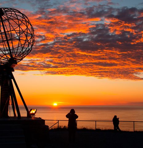 Sonnenuntergang am Nordkap mit dem bekannten Globus-Denkmal und Besuchern im Vordergrund