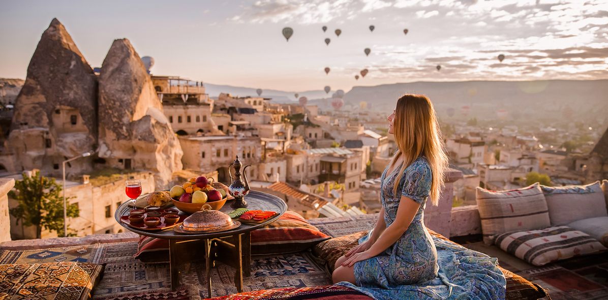 Frau vor Felsenlandschaft mit Heißluftballons in Kappadokien