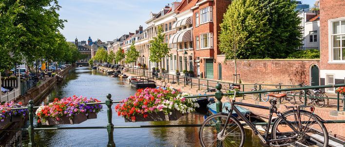 Idyllischer Kanal in Den Haag mit Blumen, historischen Häusern und Fahrrad auf der Brücke