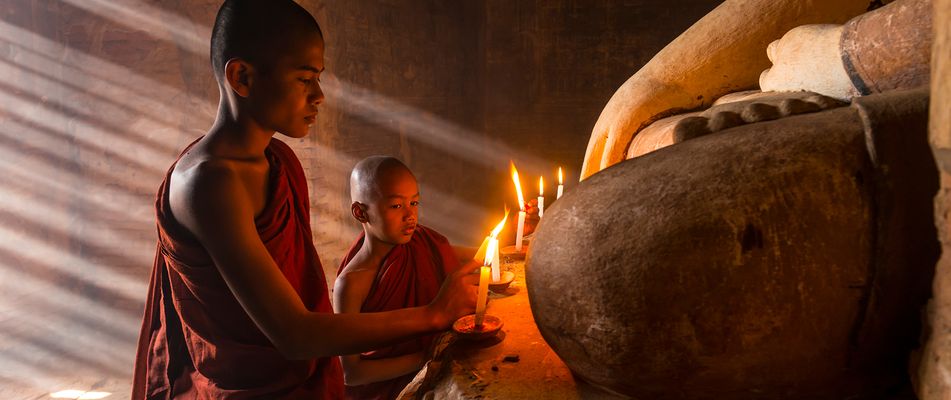 Mönche huldigem einen Buddha mit Kerzen in Kambodscha