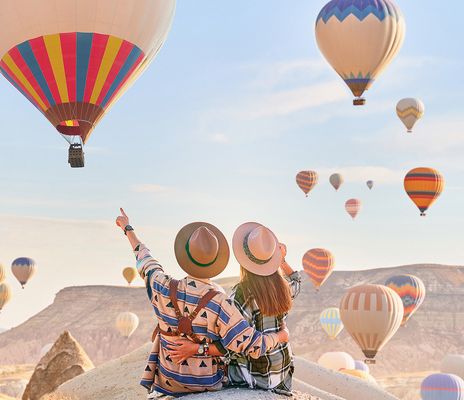 Pärchen auf Felsen mit Heißluftballons Kappadokien