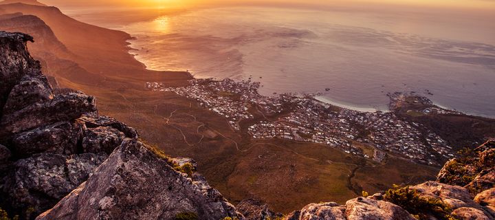 Kapstadt erstreckt sich bei Sonnenuntergang zwischen Tafelberg und Atlantikküste bis zum Horizont