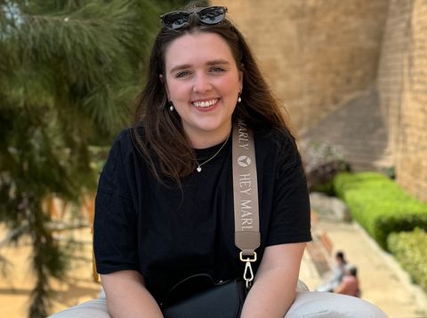 Mitarbeiterin Jana sitzt auf einer Mauer in Palma de Mallorca